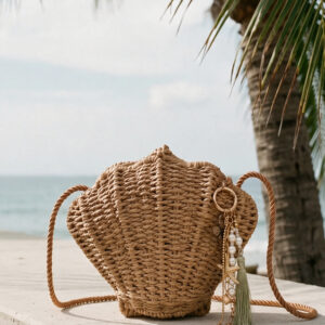 Bolso tejido Isla de Airavata en forma de concha, con correa al hombro y charms decorativos.